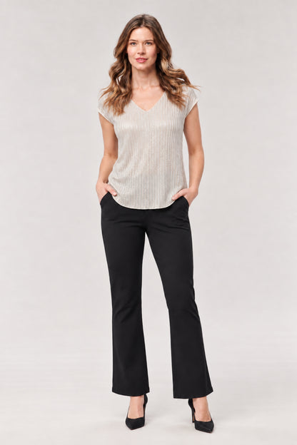 A woman modeling a light beige ribbed knit V-neck top with short sleeves and black flared pants, standing against a light gray studio background.