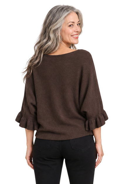 A woman with long gray hair is shown from the back wearing a brown knit sweater with three-quarter ruffled sleeves and black pants, against a plain white background.
