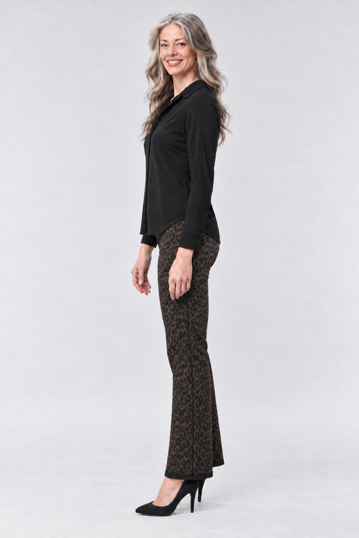 A model wearing a strapless beige and brown graphic print dress with a tiger print bodice, a matching high-waisted skirt, and a long sheer draped overlay, paired with white platform sandals, on a light gray background.